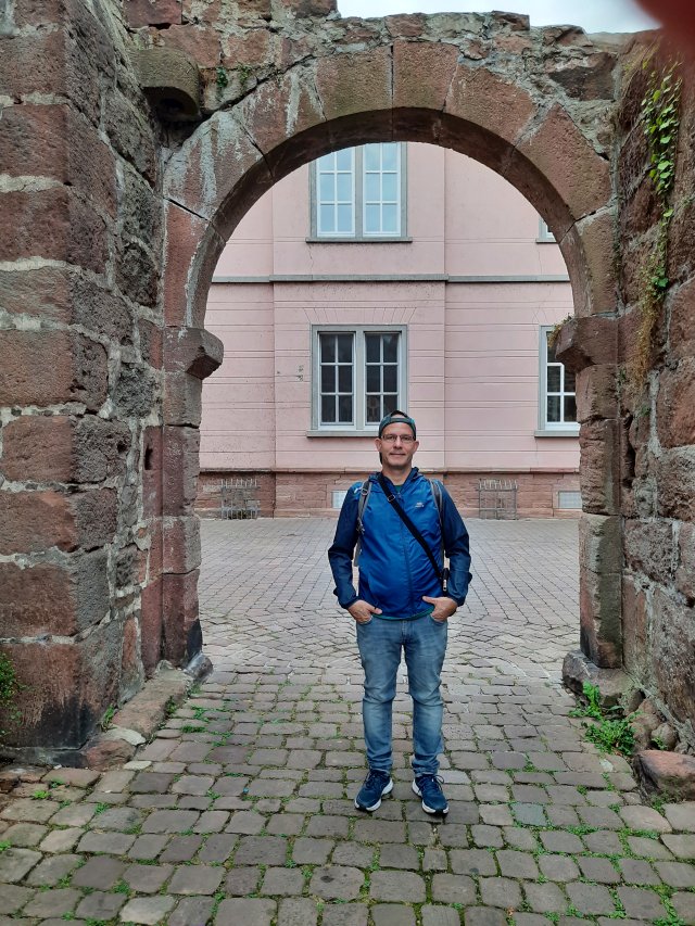 Andreas steht lächelnd vor einem massiven steinernen Rundbogentor in Eberbach