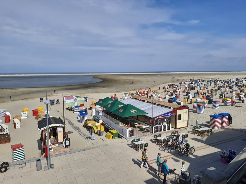 Weiter Sandstrand mit bunten Strandzelten und weitem Horizont