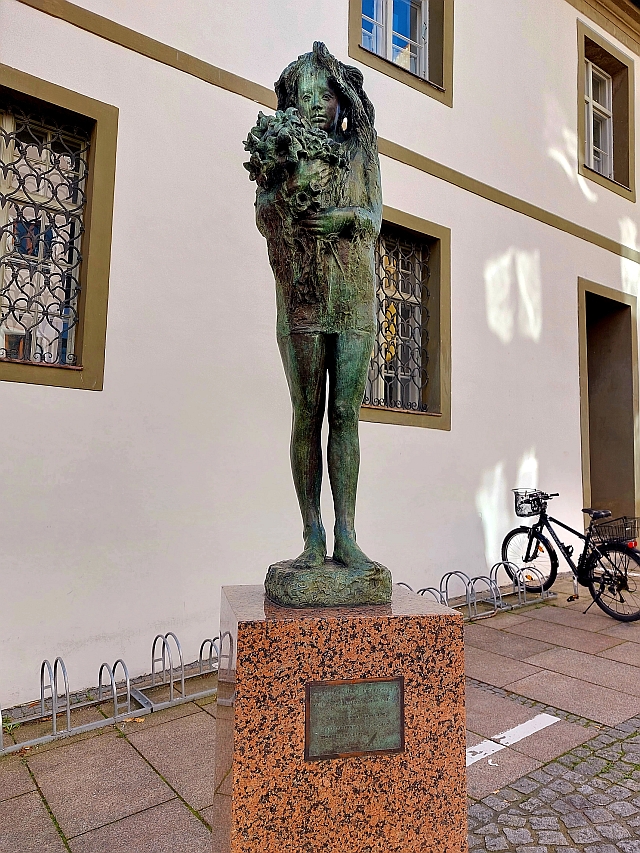 Eine Bronzestatue in der Altstadt von Füssen vor einem historischen Gebäude