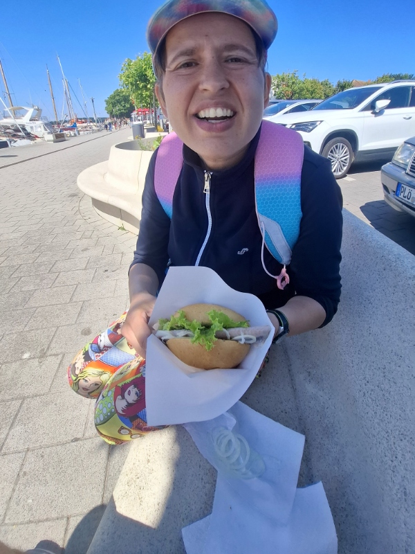 Frau ißt Matjesbrötchen in Laboe am Hafen