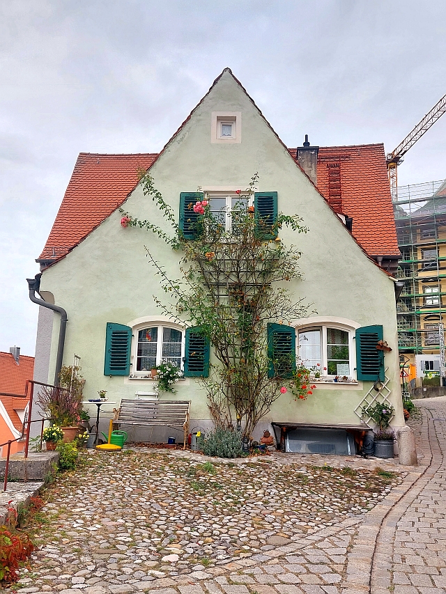 Ein traditionelles bayerisches Giebelhaus mit grünen Fensterläden und Blumenbewuchs