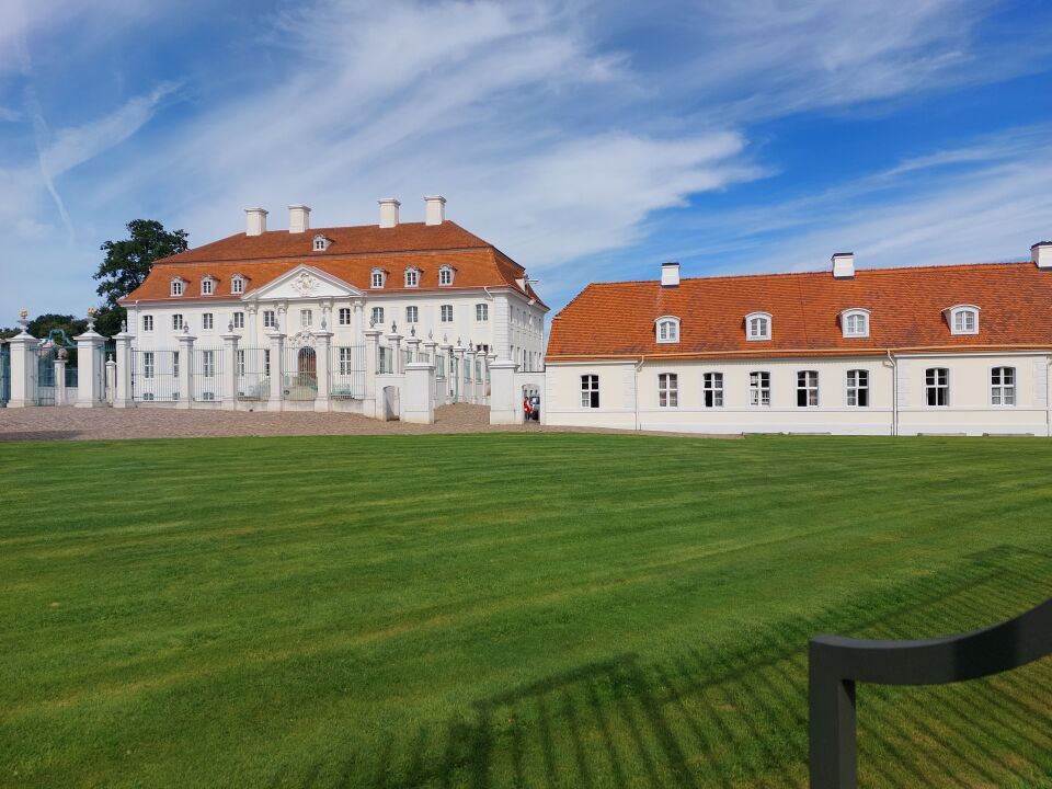 Außenansicht von Schloss Meseberg, dem weißen Barockschloss mit gepflegtem Rasen im Vordergrund