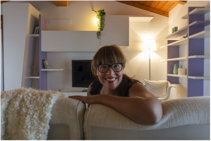 donna su un divano che sorride alla telecamera