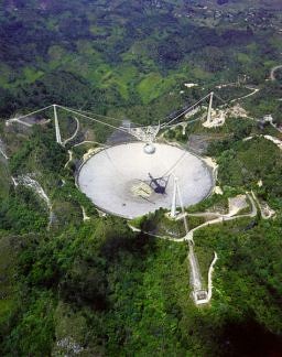 Cliquez pour agrandir l'image > L'observatoire d'Arecibo, Porto Rico Le lieu de collecte des données de SETI@home. Le radiotélescope de 300 mètres, le plus grand au monde, est menacé de fermeture pour des raisons budgétaires.La Planetary Society lutte p