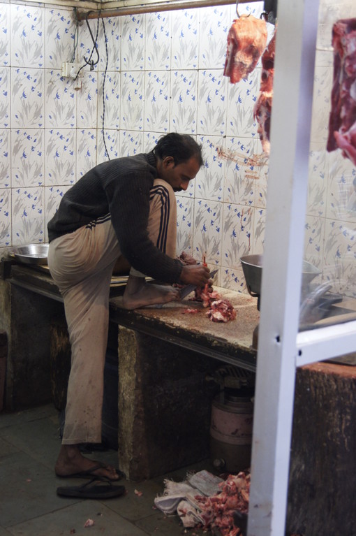 Damit er beide Hände frei hat um das Fleisch zu schneiden, hält dieser Metzger das Fleischermesser mit seinem rechten Fuss - alles Hygienekonform!