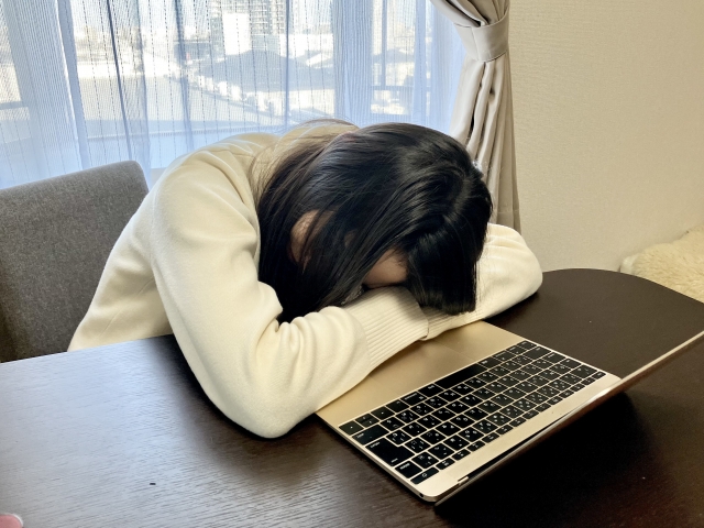 机に伏して仮眠をとっている女性