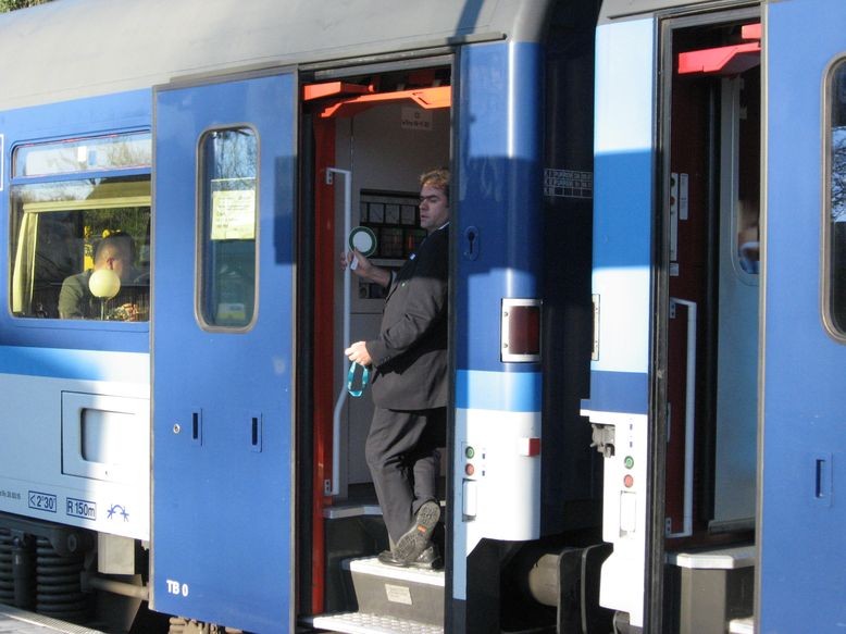 Schaffner mit Kelle in der Tür, hat Lokführer Zeichen gegeben