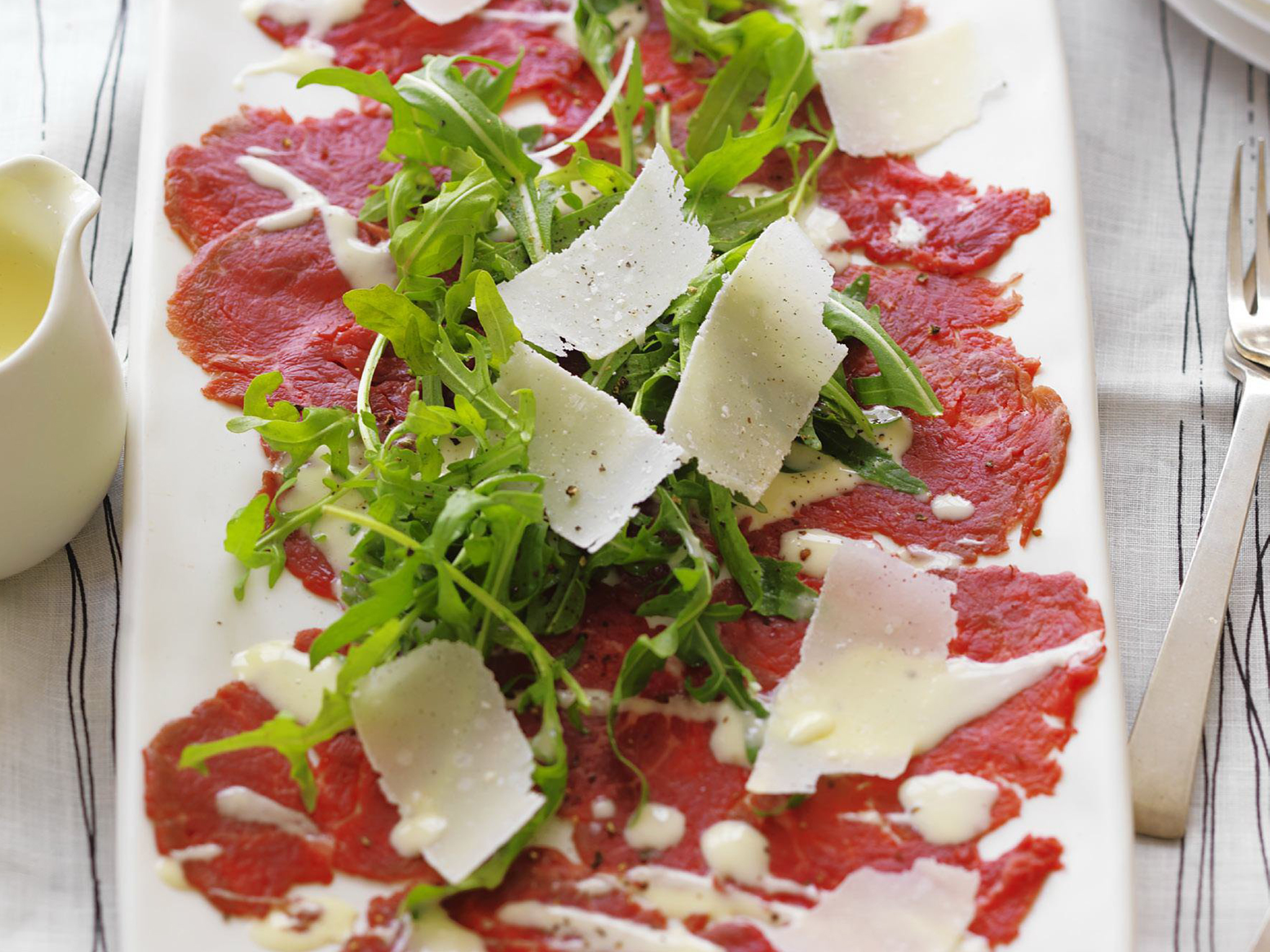 Carpaccio - Spécialité Italienne - Viande crue, finement trachée , proposée avec une salade, huile d'olive, copeaux de Parmesan et basilic