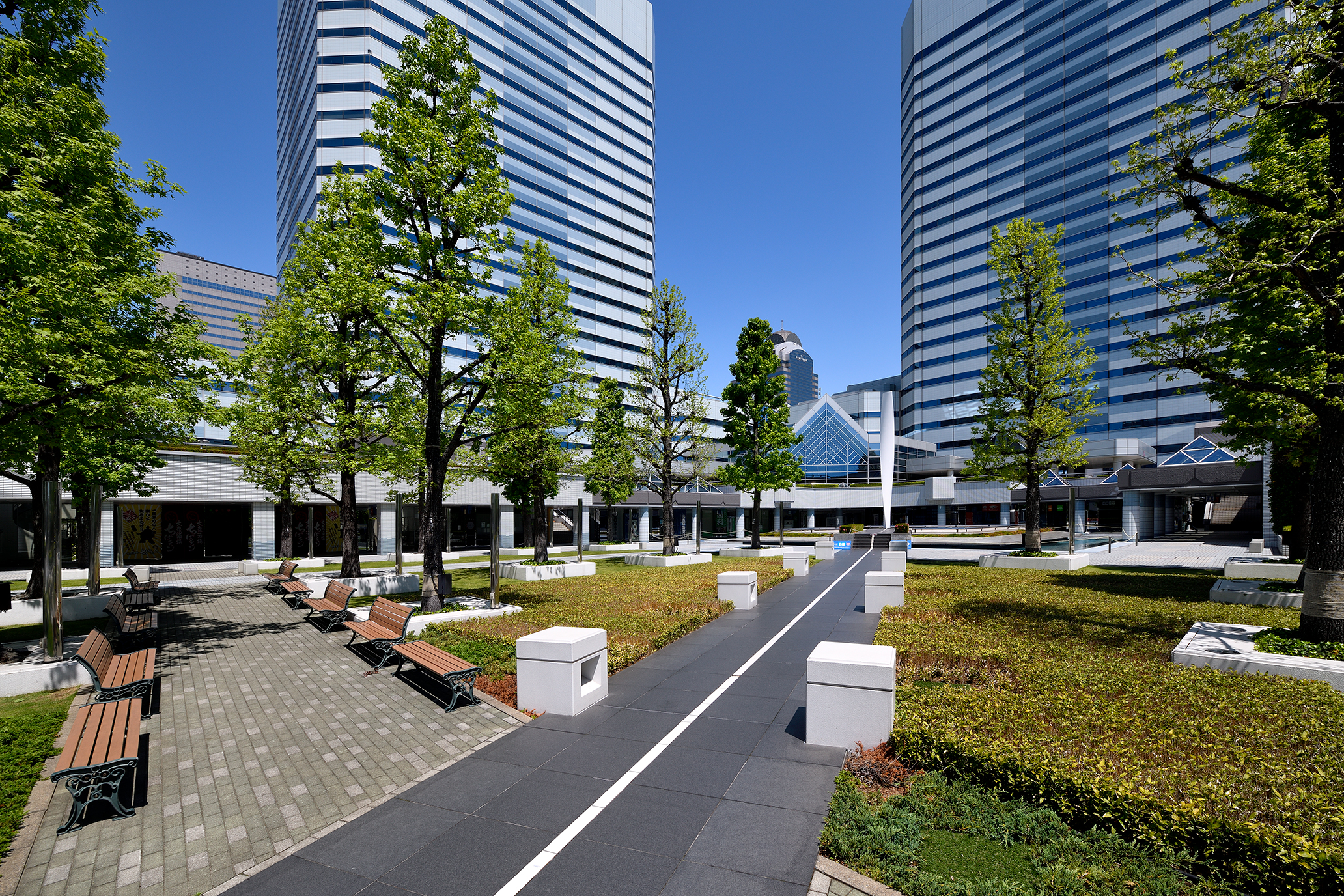 約10,000㎡に及ぶ広大なガーデンプラザ。 幕張テクノガーデンへのアプローチはここから始まります。 整然と配置された樹木の間を通り抜け、敷地全体の中心にそびえるモニュメントに向かうとそこには噴水のある池に囲まれたステージがあり、水と木々が創り出す空間は、働く人々が四季に触れながら自然の中でゆったりと散策、休憩し、思索や語らいのできる場となるよう配慮されています。 また、プラザは一部が2層の回遊