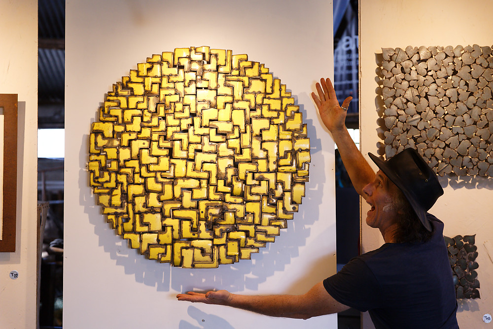 Tableau en acier jaune de forme circulaire et en présence de l'artiste