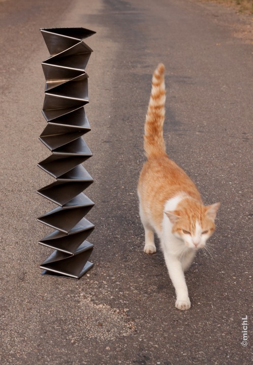 petite sculpture en acier placée à côté d'un chat
