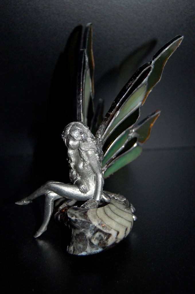 Elfe: statuette en étain avec ailes en verre posée sur fossile