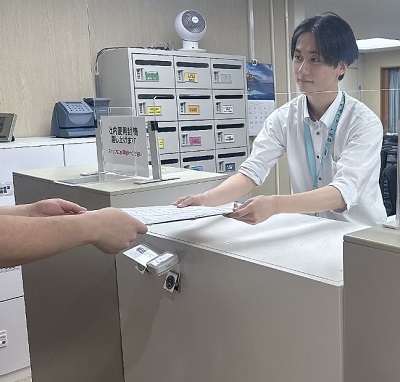 メール室でお客様対応を行うYさんの様子
