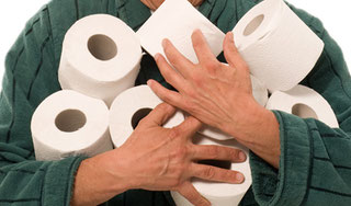 Mensch im Bademantel hält viele Rollen Toilettenpapier in den Händen.