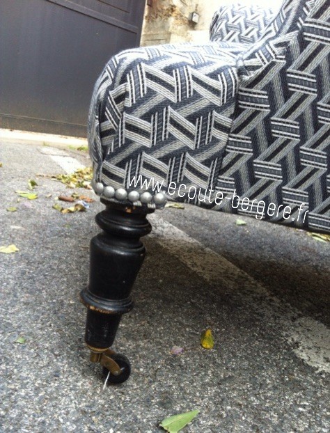 Zoom sur le pied avant d'un fauteuil anglais, fini par un pli en V maintenu par clous nickel mat au dessus du pied Napoléon 3