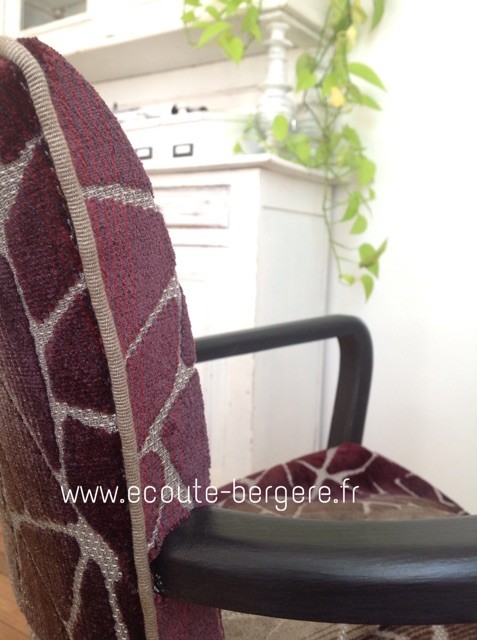Détail de la finition d'un fauteuil Bridge patiné noir mat, tissu en velours aubergine dégradé,,passepoil beige sur l'arête du fauteuil.