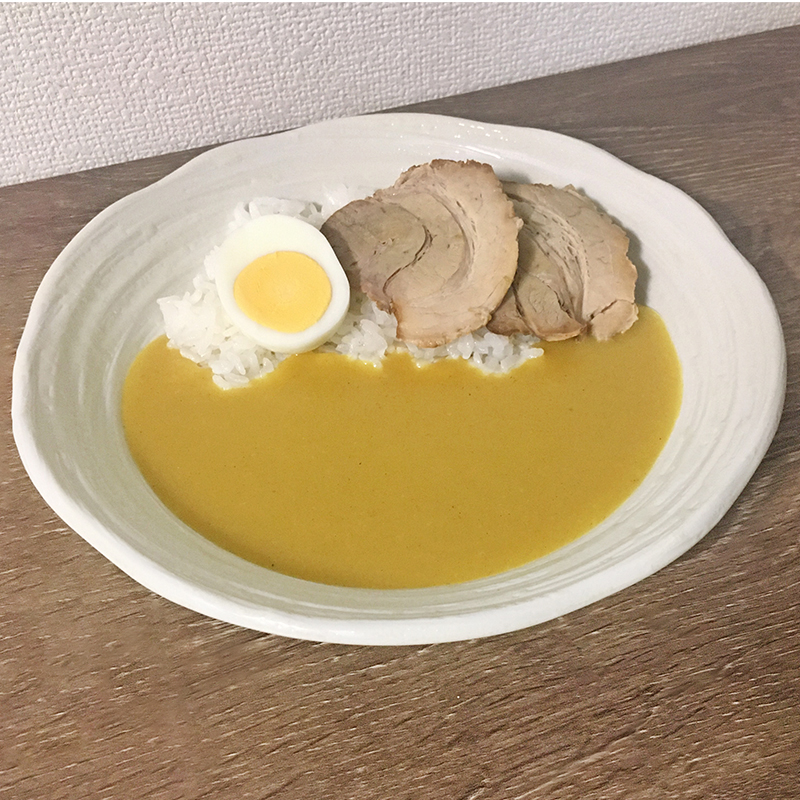 ご飯にカレーを１人分かけて、トッピングのチャーシューとゆで玉子をのせて完成