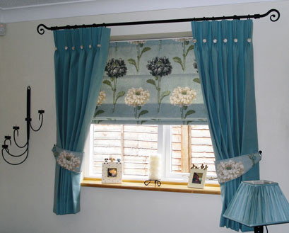 Triple pinch pleat curtains with contrast buttons with tie-backs matching the roman blind inset into the window