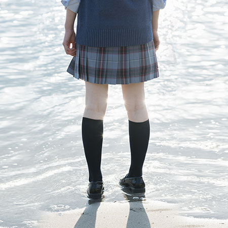 海辺に佇む女子高校生の後ろ姿