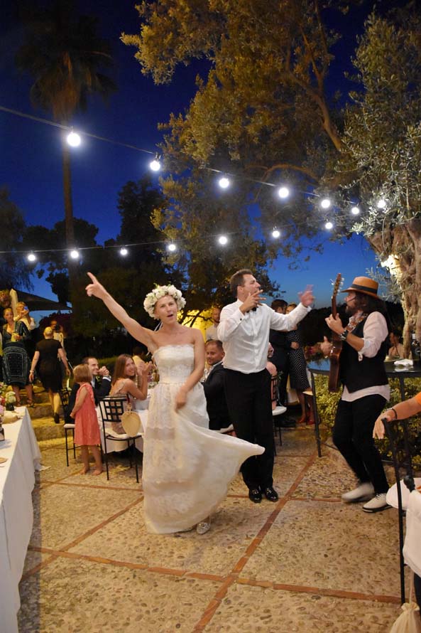 Brautpaar tanzt ausgelassen bei einer Hochzeitsparty unter Lichterketten im Freien