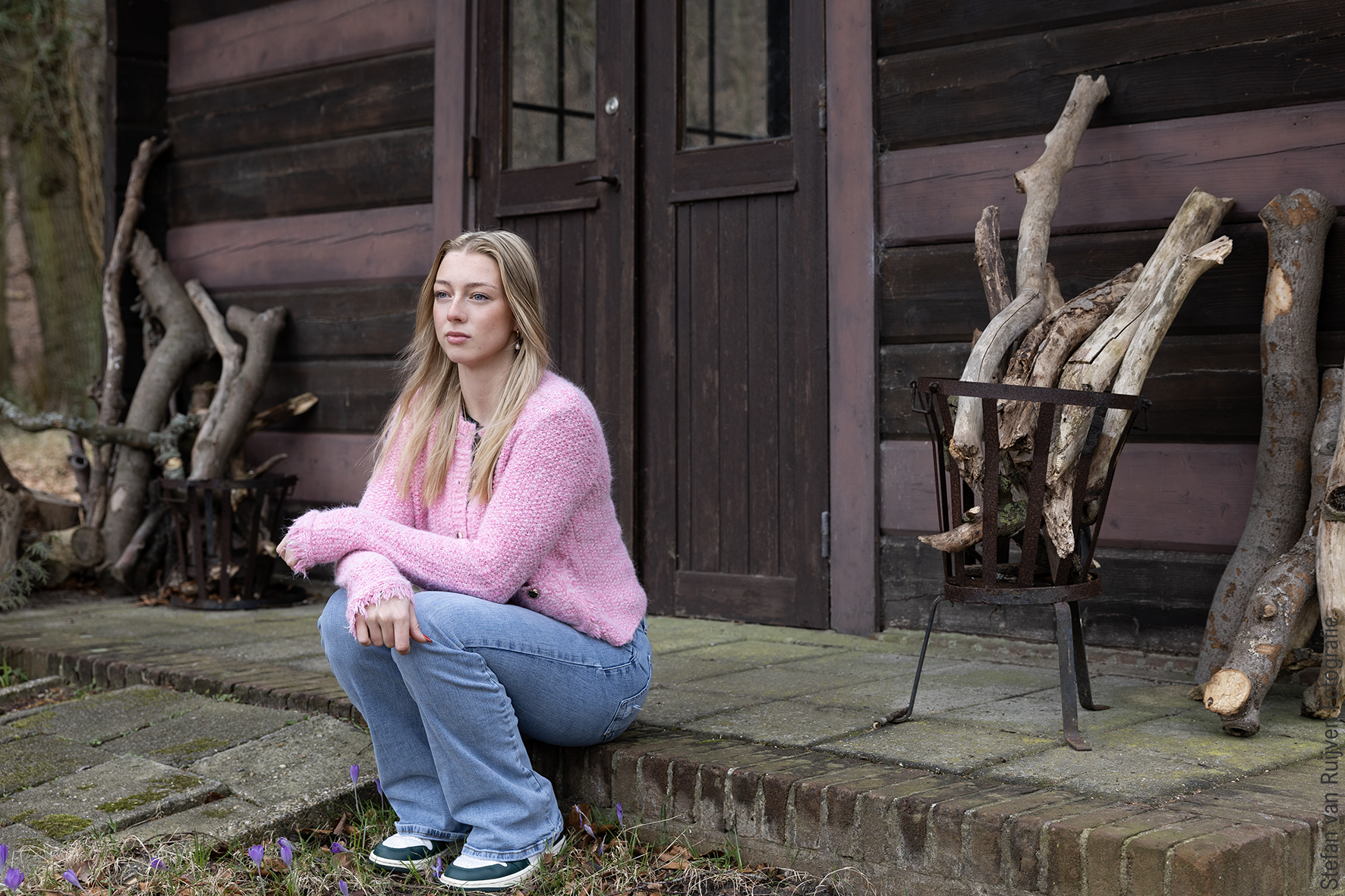 Daisy zit in een roze trui en jeans en sneakers voor een huisje. Foto is gemaakt door Stefan van Ruijven Fotografie tijdens de Fotoshoot Dag op 27 februari 2026 in Studio Duinlust