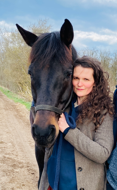 Mädchen auf Pferd vor blauem Himmel mit Wolken