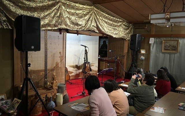 新小岩にある應無寺(おうむじ)の音楽ステージにフォークギターがセットしてある場面