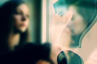 Frau schaut fragend aus dem Fenster