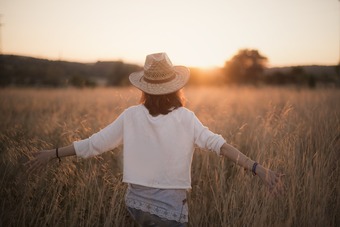 Frau läuft durchs Weizenfeld in Abenddämmerung