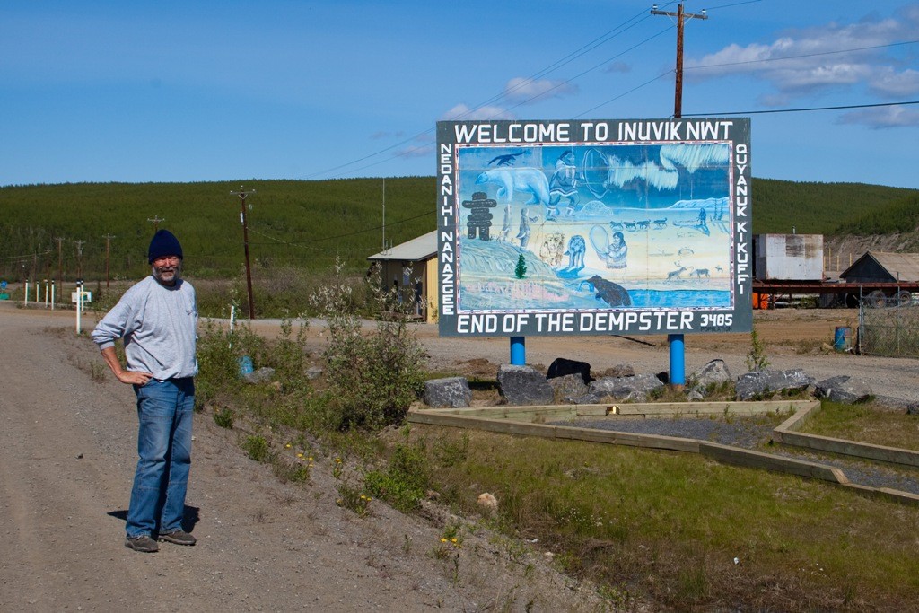 In Pose vor der Hinweistafel des Endes vom Dempster HWY in Inuvik, die zu diesem Zeitpunkt dort lebenden Einwohner, 3.485!