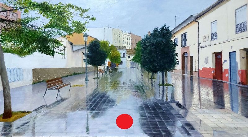 Calle peatonal mojada en Patraix con árboles, bancos y reflejos en el pavimento tras la lluvia.