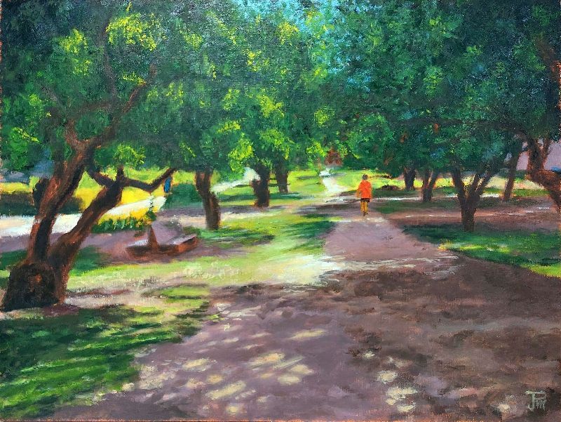 Sendero arbolado en el antiguo cauce del Turia, con luz entre las hojas y figura caminando al fondo.
