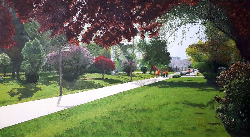 Paseo del Jardín del Turia con árboles frondosos, césped, personas caminando y edificios urbanos al fondo.