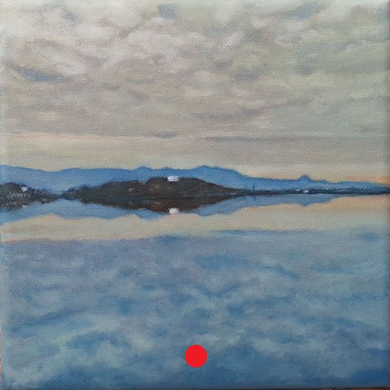 Montaña reflejada en un lago tranquilo, cielo nublado con claros y vegetación baja en primer plano.