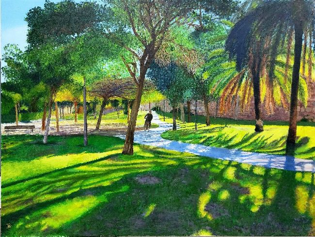 Contraluz de árboles en el Jardín del Turia, con ciclista avanzando por el carril bici entre luces y sombras.
