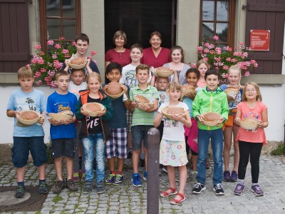 Kinder des Sommerferienprogramms präsentieren selbstgebackenes Brot