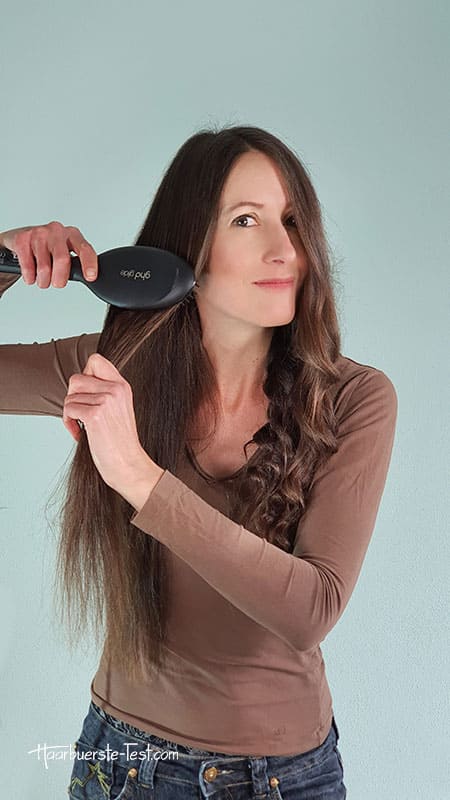 Das Glätten krauser Haare mit einer Glättbürste ist sehr intuitiv. Haarsträhne abteilen und mit einer Hand halten. Glättbürste ansetzen.