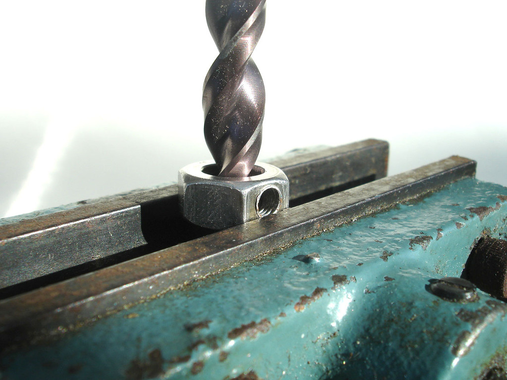 Grip 10mm nut flat in vice and drill through with 10mm bit