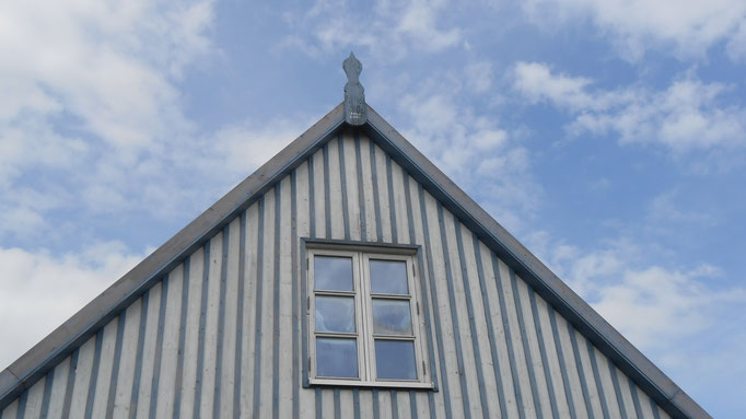 Der blau-weiß gestreifte Giebel des Ferienhauses vor blauem Himmel.