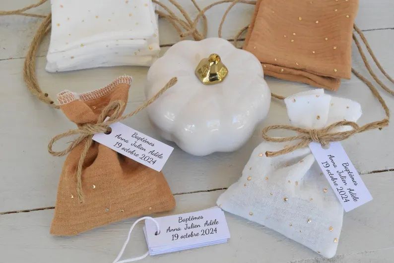 Le pochon à dragées en double gaze de coton, dans les coloris camel à pois doré et blanc à pois doré, réunit tout ce qu'on recherche pour une cérémonie d'automne réussie 