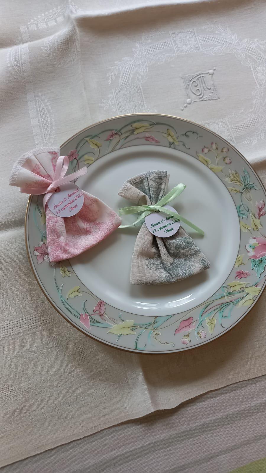 pochons dragées fiançailles toile de jouy vert et rose posé sur une assiette vintage