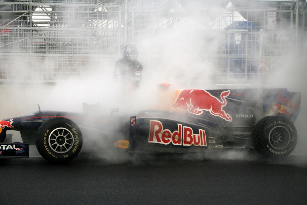 Sebastian Vettel cerca di spegnere l'incendio della sua vettura 