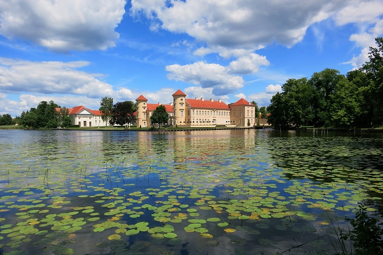 Tourismus-Öffnung nach Corona im land Brandenburg -Schloss Rheinsberg hinter einem See voll von Seerosen