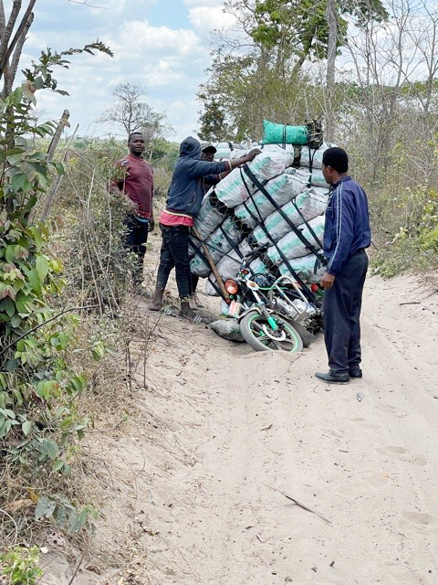 Eine Gruppe Afrikaner mit einem sehr voll beladenem Moped.