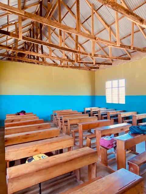 Klassenzimmer mit leeren Schulbänken aus Holz.