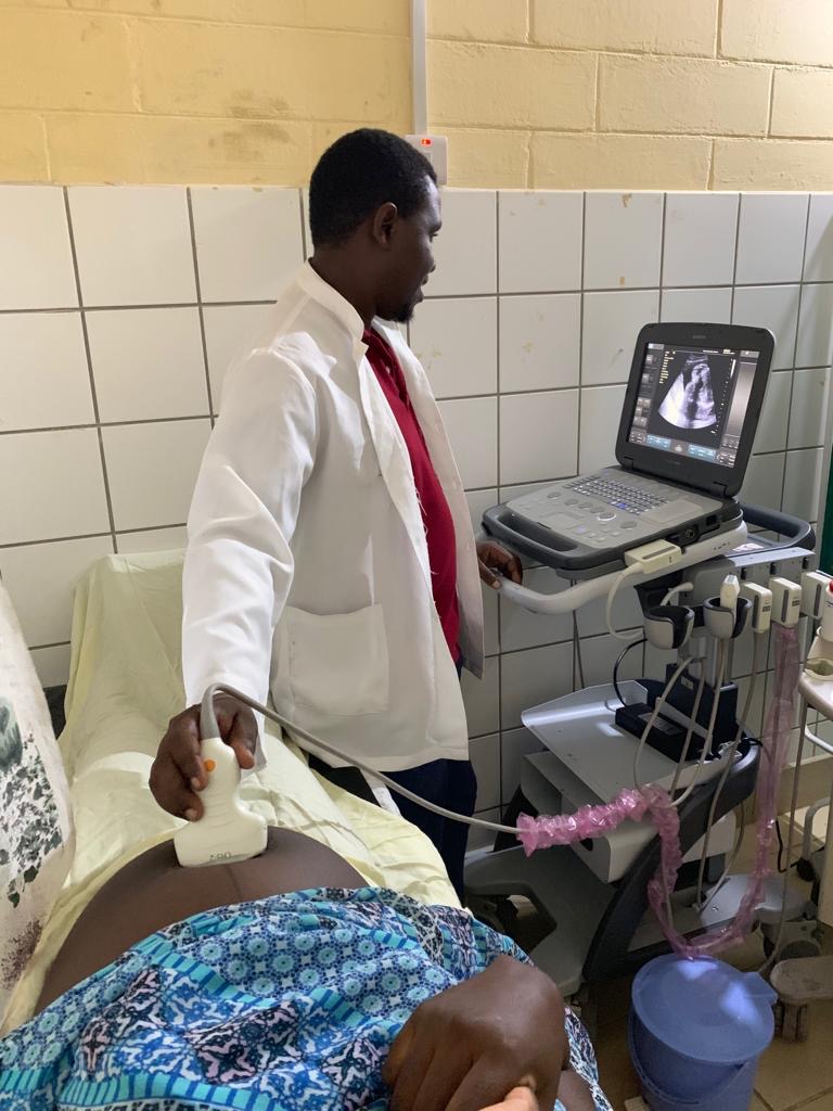 Dr. Ronald bedient das neue Ultraschallgerät im Krankenhaus, Gerät auf Rollständer neben ihm.