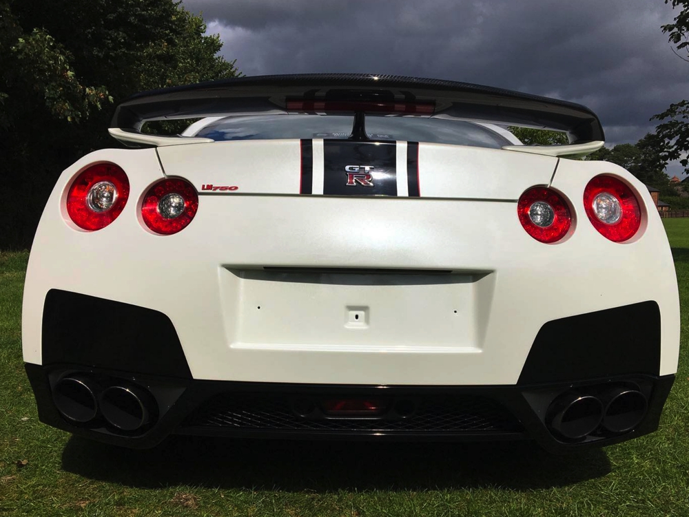 Back view of white Nissan GTR LM750 in field