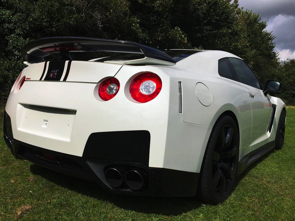 Rear side view of white Nissan GTR LM750 in field