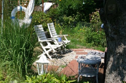 Zwei weiße Gartenstühle bieten zusätzlichen Sitzplatz