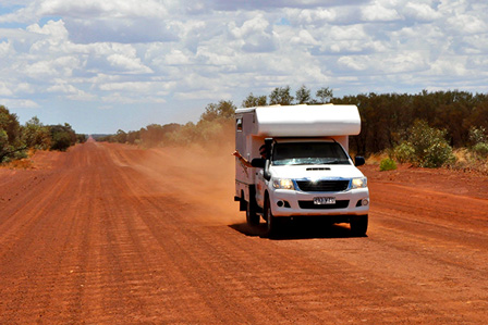 Weißes Wohnmobil auf roter Sandpiste im australischen Outback 2026